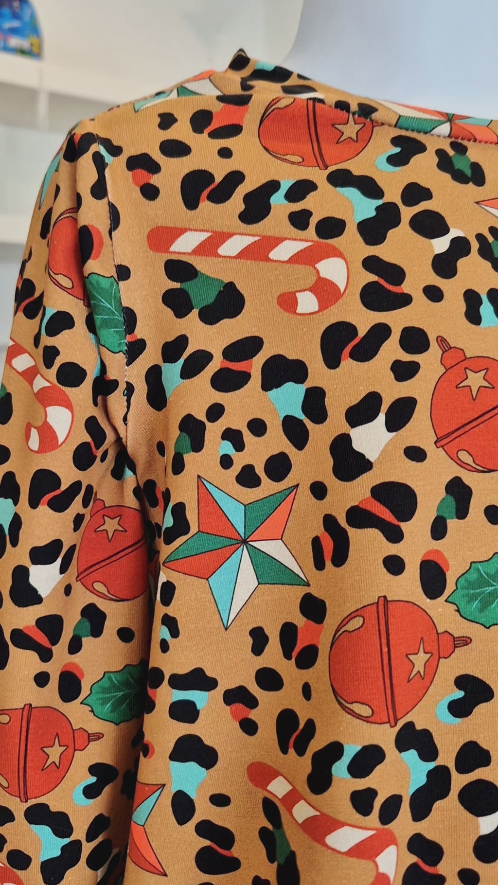 Video showing the Christmas dress, the print has a browny gold background, with a leopard print pattern, interspersed with candy canes, stars and baubles. A modern, stylish take on the Christmas dress